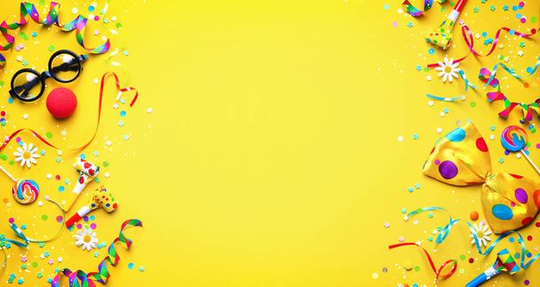 Colorful carnival or birthday party background with streamers, confetti and funny faces formed from bow tie, hat, eyeglasses and lips - Фото, изображение