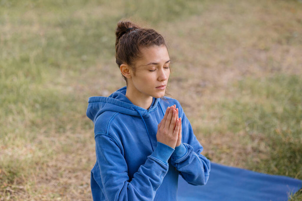 donna con i capelli ricci medita in un parco. yoga e meditazione per la salute mentale e fisica - Foto, immagini