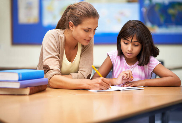 Shes a dedicated educator. Shot of a teacher helping her student with her work in the classroom. - Photo, image
