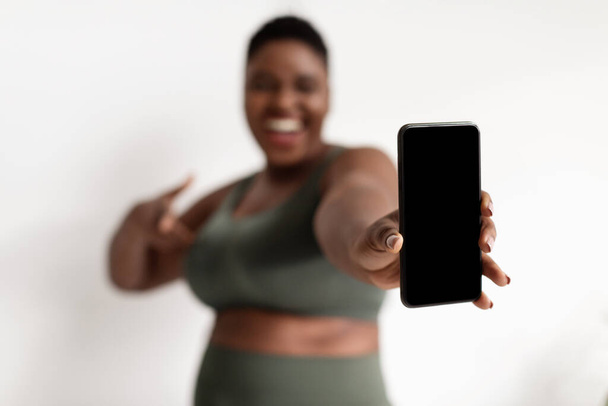 Okostelefon üres képernyővel túlsúlyos fekete hölgy kezében - Fotó, kép