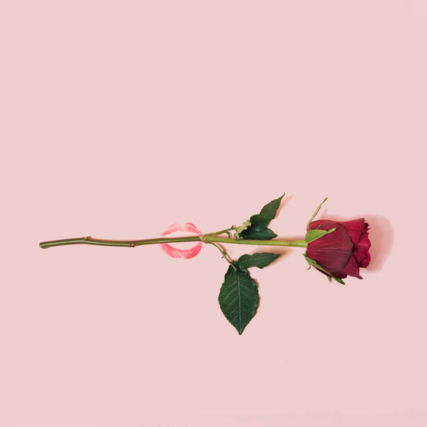 Kreative Valentinstags-Komposition mit Lippenstift-Kuss und roter Rose. Minimal flach lag mit Kopierraum. Romantisches Konzept auf pastellfarbenem Hintergrund. - Foto, Bild