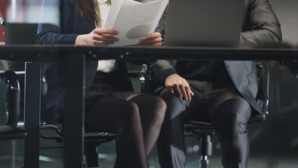 Сексуальні домагання на роботі. Бізнесмен турбує жінку колегу під час зустрічі, торкаючись її коліна під столом
 - Кадри, відео