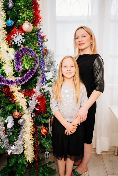 ξανθιά μαμά και μικρή κόρη στο χριστουγεννιάτικο δέντρο. - Φωτογραφία, εικόνα