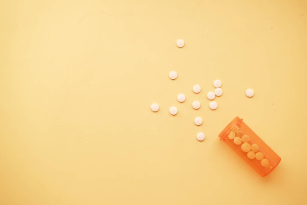  white color medical pills spilling on yellow background  - Foto, afbeelding