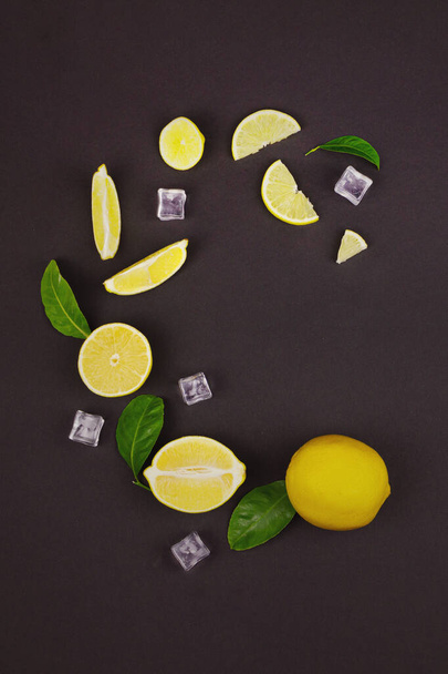 Composición de fruta fresca de limón con hojas verdes y cubitos de hielo sobre un fondo marrón. Ingredientes para bebida de verano y limonada - Foto, Imagen