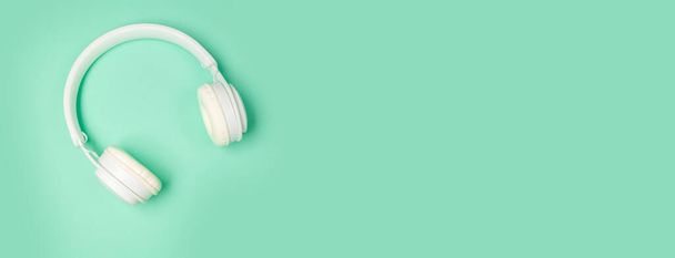 Captura de estudio de auriculares inalámbricos blancos modernos aislados sobre fondo de menta verde. Concepto musical con copyspace - Foto, imagen