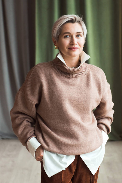 fashion woman in brown oversize sweater and trousers standing in modern work place or office - Valokuva, kuva