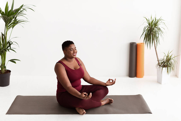 Señora negra grasa pacífica en ropa deportiva que tiene práctica de yoga - Foto, Imagen