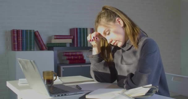 Unavený po dlouhém používání počítače mladá žena sundá brýle třít nos most snižuje bolestivé pocity odpočinku sedět na pracovišti. - Záběry, video