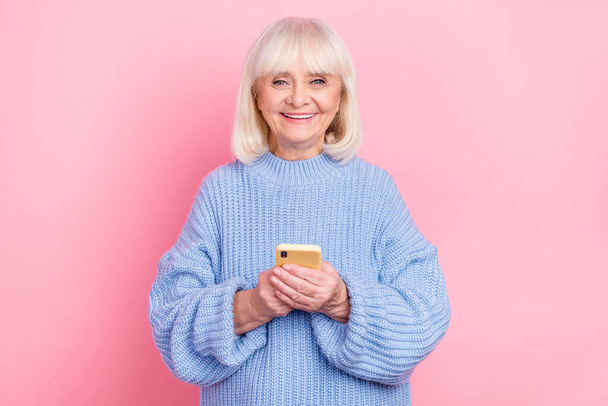 Portrait of attractive cheerful grey-haired woman using device gadget chatting isolated over pink pastel color background - Фото, изображение