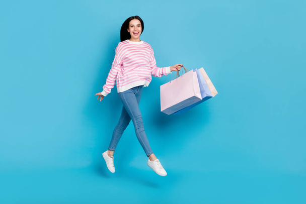 Full size photo of young lady jump up shop mall store discount present isolated over blue color background - Fotó, kép