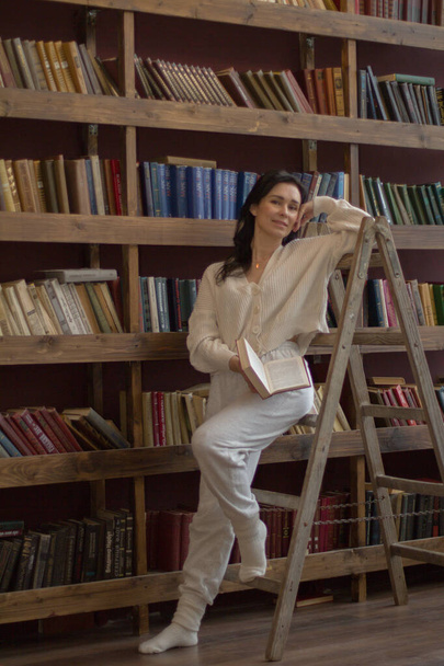 een vrouw in de bibliotheek leest een boek - Foto, afbeelding
