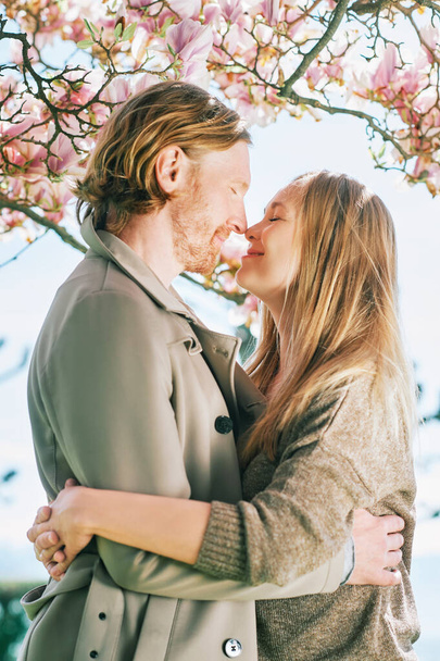 Happy romantic couple kissing under blooming tree - Foto, imagen