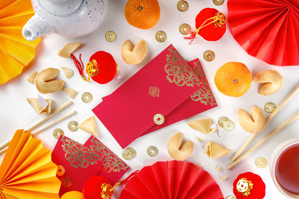 Anno nuovo cinese sfondo. Flatlay giallo oro e rosso con decorazioni tradizionali cinesi di Capodanno, buste con desideri, monete d'oro, ventagli, lanterne cinesi, arance e tè - Foto, immagini