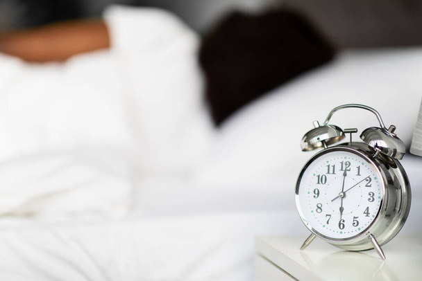 Alarm op bed over onherkenbaar slapende zwarte dame - Foto, afbeelding