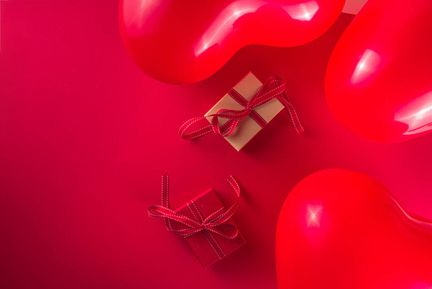 Valentine day sweet holiday background with red heart shaped balloons, rose flowers and gift boxes on red background top view frame copy space, mockup for Valentines greeting card - Фото, зображення