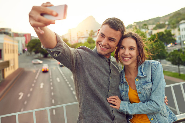 Sentimental selfies. Shot of a happy young couple taking a selfie together in the city. - 写真・画像