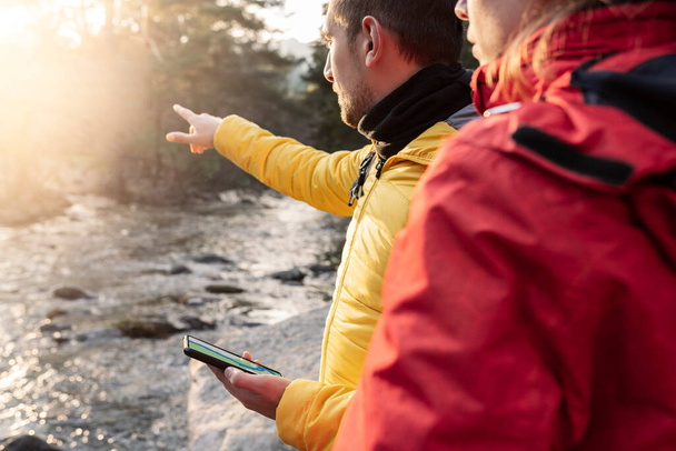 close-up detail of hands looking at map on mobile, forest hiking, couple in the mountains at sunset - Фото, зображення