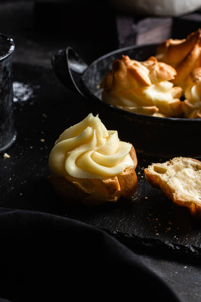 Profiteroles with custard on a dark table. Eclairs - Photo, Image