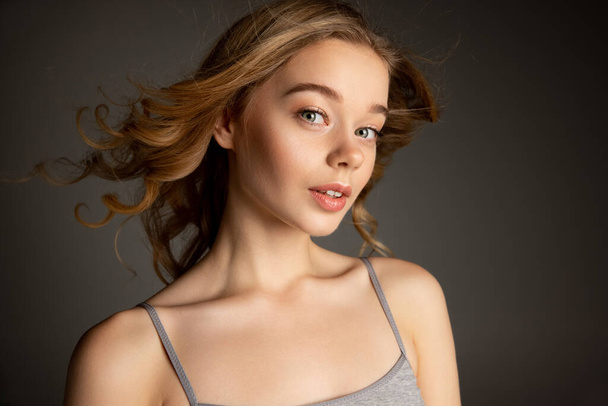 Close-up portrait of young beautiful girl with day makeup isolated over gray studio background. Natural beauty concept. - 写真・画像