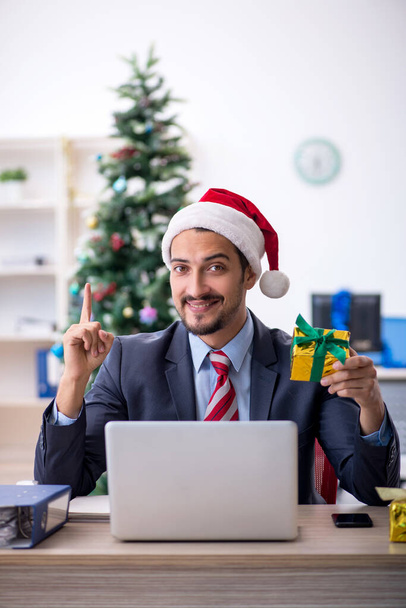 Mladý muž zaměstnanec slaví Vánoce na pracovišti - Fotografie, Obrázek