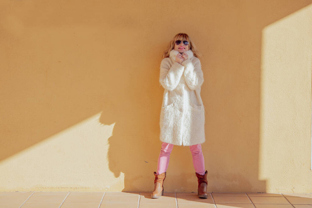 доросла жінка в пальто на стіні вулиці
 - Фото, зображення