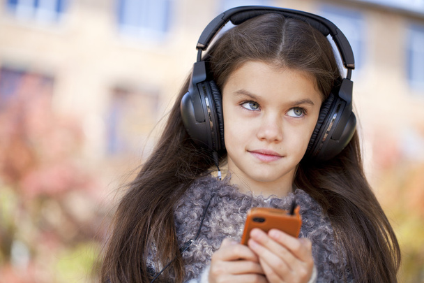 Beautiful little girl listening to music on headphones - Valokuva, kuva