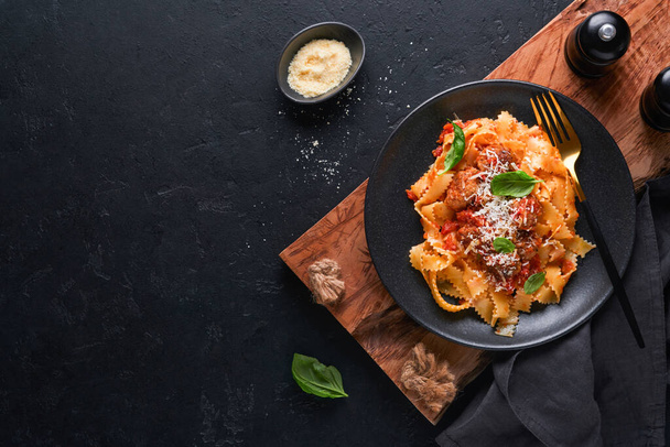 Tagliatelle pasta with meatballs in tomato sauce, basil and parmesan cheese on black stone or concrete background. Traditional Italian dish and cuisine. Top view with copy space. - 写真・画像