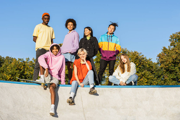 Multicultural group of young friends bonding outdoors and having fun - Stylish cool teens gathering at urban skate park - Zdjęcie, obraz