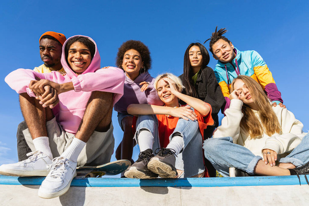 Multicultural group of young friends bonding outdoors and having fun - Stylish cool teens gathering at urban skate park - Фото, изображение