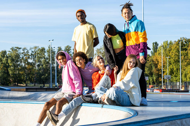 Multicultural group of young friends bonding outdoors and having fun - Stylish cool teens gathering at urban skate park - Foto, Bild