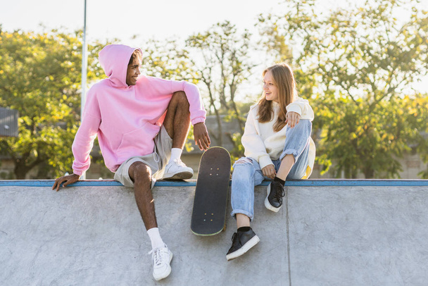 Multicultural group of young friends bonding outdoors and having fun - Stylish cool teens gathering at urban skate park - Photo, image