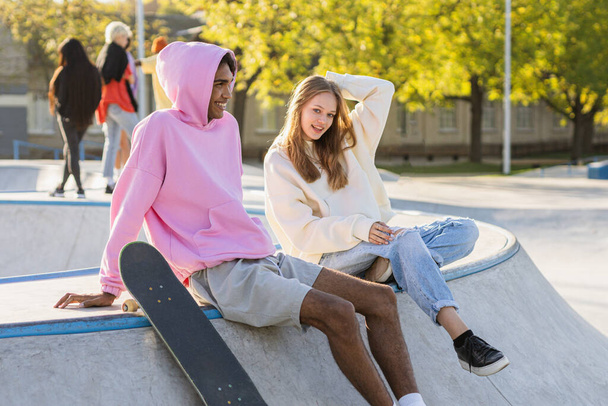 Multicultural group of young friends bonding outdoors and having fun - Stylish cool teens gathering at urban skate park - 写真・画像