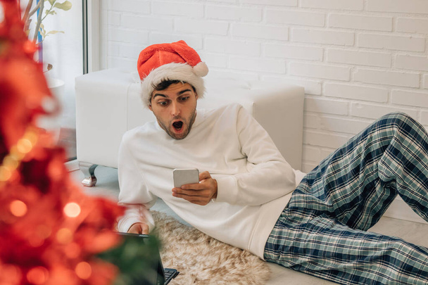Mann zu Hause entspannt zu Weihnachten mit Handy - Foto, Bild