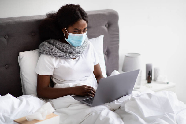 Sick black woman in face mask surfing on Internet - Zdjęcie, obraz