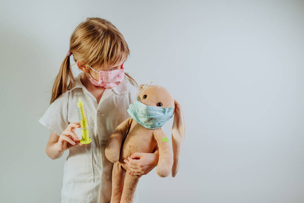 irreconocible niña usando médico bata celebración suave juguete conejito - Foto, imagen