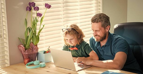 glücklicher Vater, der seinem Schulkind beim Brillenlernen mit dem Computer zu Hause hilft, Kindheit - Foto, Bild