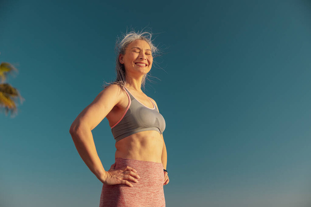 Hymyilevä nainen lepää rannalla harjoittelun jälkeen - Valokuva, kuva