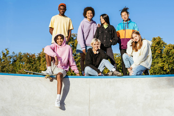 Multicultural group of young friends bonding outdoors and having fun - Stylish cool teens gathering at urban skate park - Foto, afbeelding