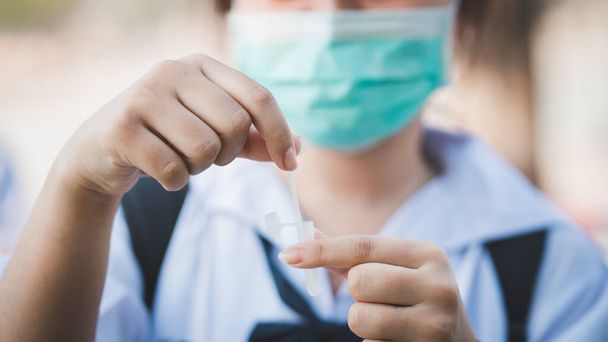 Egyenruhás lány diák tampon COVID-19 teszt Rapid Antigen teszt készlet otthon egy pamut orrváladék - Fotó, kép