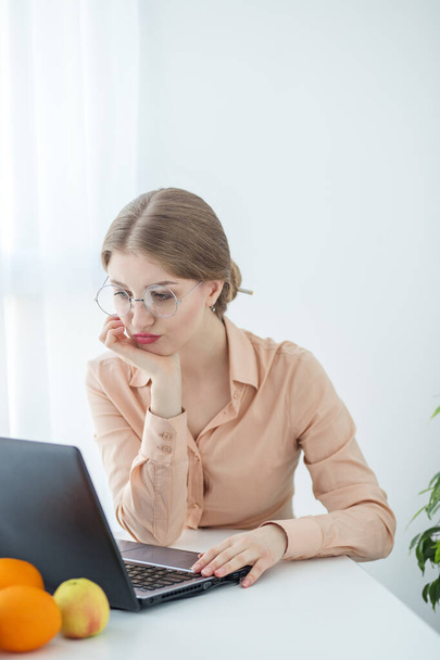Femme avec des lunettes portant un chemisier beige. Étudiante utilise ordinateur portable et Internet dans les études. Vertical. - Photo, image