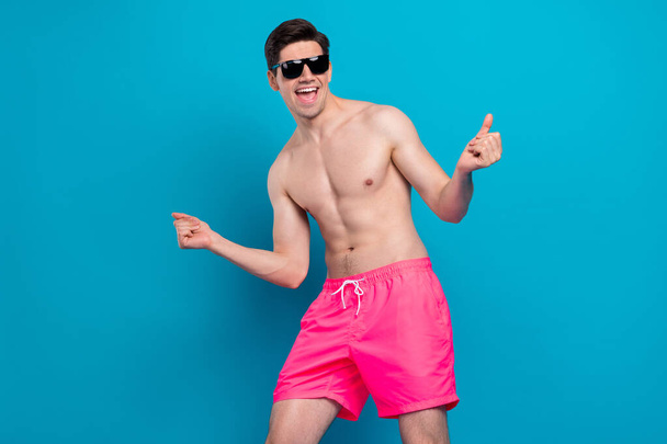 Photo of attractive funky young man naked torso dark eyewear dancing smiling isolated blue color background - Valokuva, kuva