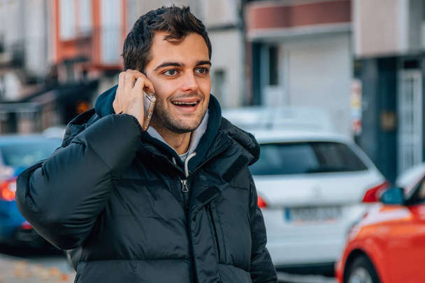 Mann in Winterjacke auf der Straße telefoniert - Foto, Bild