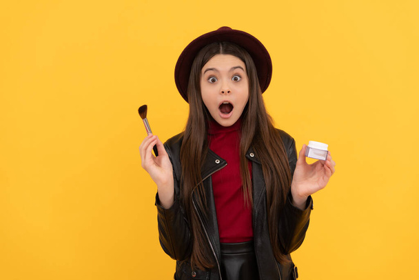 shocked kid in hat hold makeup brush and powder on yellow background, skincare - Photo, Image