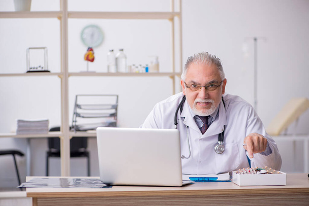 Old male doctor working in the clinic - Photo, Image