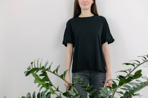 Woman wearing black blank t-shirt with space for your logo, mock up or design indoors - Фото, изображение