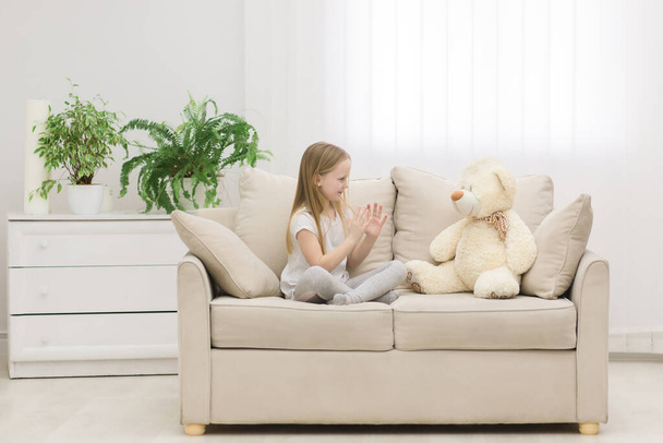 Photo of blond girl talking to her toy plush friend. - Foto, imagen