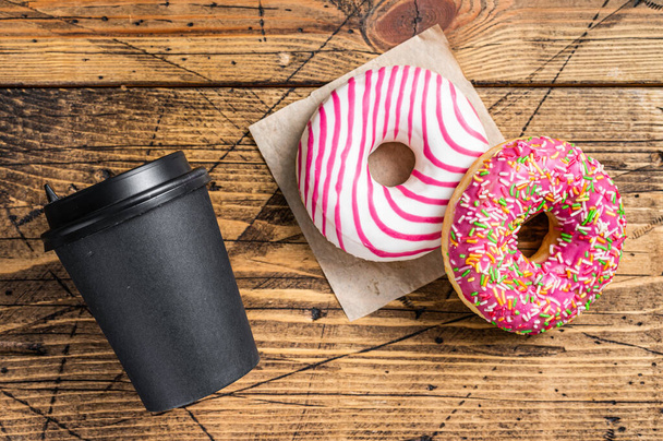 Pink glazed donuts on a kitchen table with coffee. Wooden background. Top view - Photo, Image