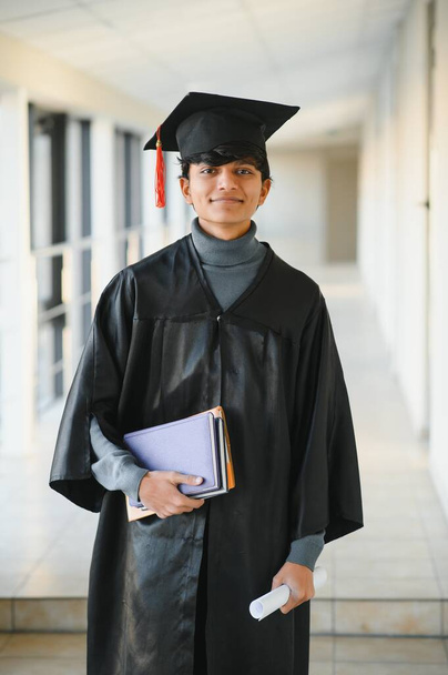 Portrait of indian handsome male graduate in graduation robe and blured background. - Photo, Image