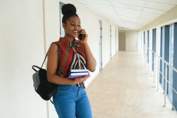 Sırt çantalı, üniversite geçmişinde gülümseyen Afro-Amerikan öğrenci kız. Teknoloji, eğitim, eğlence kavramı - Fotoğraf, Görsel